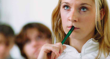 Ein Foto von einer Frau, die nachdenkt mit einem Stift in der Hand und halb im Mund.